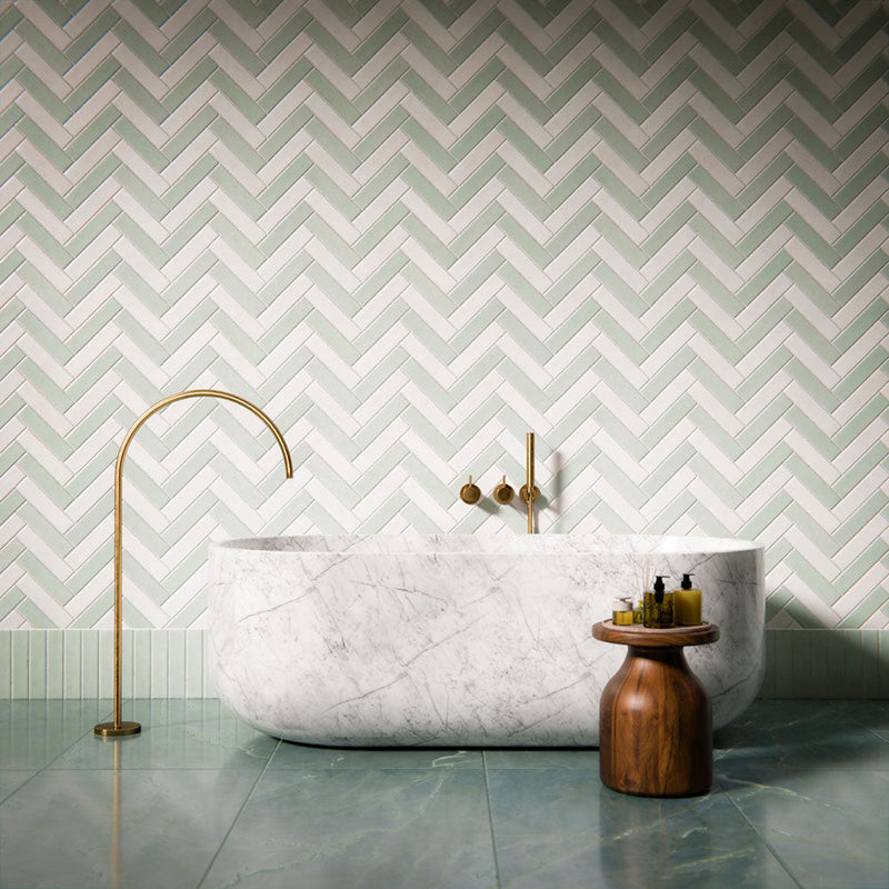 Bathroom setting featuring Madison brick tiles arranged in a soft sage and white herringbone pattern, paired with a marble bath, brushed brass fixtures and a calm, contemporary palette.