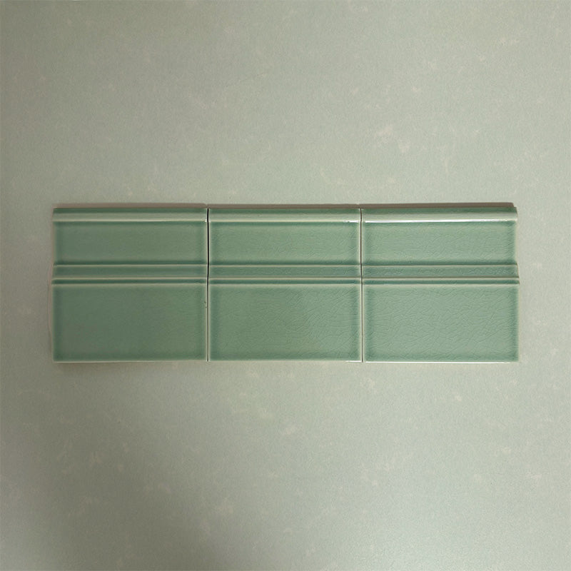 Flat lay of Finchley Lime Green 15 × 15cm ceramic skirting tiles with a crackle glaze finish, designed to create a smooth, decorative transition between wall and floor in classic interior spaces.