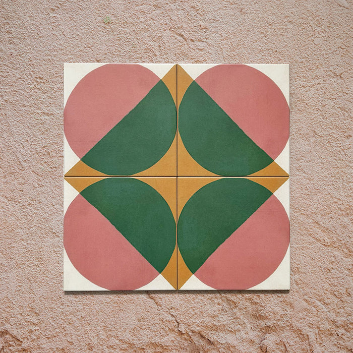 Group image showing four Geometry Paloma 20x20cm geometric patterned tiles arranged to form a circular motif, featuring pink and green semicircles with mustard and cream corner accents, photographed against a textured stone background.