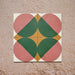 Group image showing four Geometry Paloma 20x20cm geometric patterned tiles arranged to form a circular motif, featuring pink and green semicircles with mustard and cream corner accents, photographed against a textured stone background.