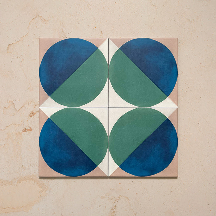 Group image showing four Geometry Ocean 20x20cm geometric patterned tiles arranged to create a circular motif, featuring blue and green semicircles with sand and white corners, photographed against a neutral stone background.