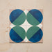 Group image showing four Geometry Ocean 20x20cm geometric patterned tiles arranged to create a circular motif, featuring blue and green semicircles with sand and white corners, photographed against a neutral stone background.