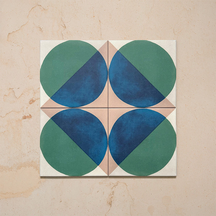 Group image showing four Geometry Ocean 20x20cm geometric patterned tiles arranged to create a circular motif, featuring blue and green semicircles with sand and white corners, photographed against a neutral stone background.