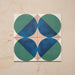 Group image showing four Geometry Ocean 20x20cm geometric patterned tiles arranged to create a circular motif, featuring blue and green semicircles with sand and white corners, photographed against a neutral stone background.
