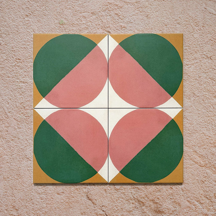 Group image showing four Geometry Paloma 20x20cm geometric patterned tiles arranged to form a circular motif, featuring pink and green semicircles with mustard and cream corner accents, photographed against a textured stone background.
