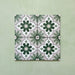 Flatlay featuring four Clarence House Jade Mini 15x15cm Victorian Moroccan-style porcelain tiles, forming a repeating geometric floral pattern in soft green, white, and grey on a light green background.