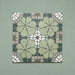 Four Bloom Green 20x20cm Moroccan-style ceramic tiles displayed together, featuring a symmetrical floral pattern in green, grey, and white tones on a soft green background.
