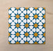 Close-up of four Agraba Sunshine 20x20cm Moroccan-style ceramic tiles arranged together, showing a geometric star pattern in blue, mustard yellow, and white on a neutral sandy background.