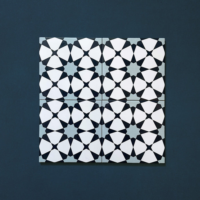 Close-up of four Agraba Azul Blue 20x20cm Moroccan-style ceramic tiles arranged together, showing a geometric star pattern in navy, light blue, and white tones on a deep blue background.