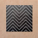 Alhambra Zig Zag Black 20x20cm Moroccan tiles arranged in a four-tile layout, displaying bold black chevron stripes with crisp white lines for a striking geometric effect.