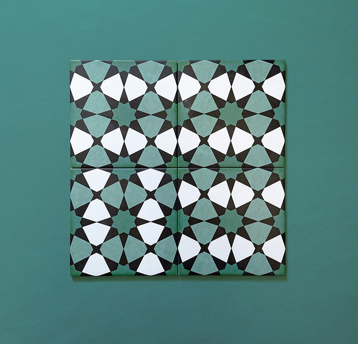 Four Agraba Verde 20x20cm Moroccan-style tiles displayed on a teal background, showing the repeating green and white geometric star pattern for a classic handcrafted look.