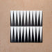 Four Alhambra Tavla 20x20cm Moroccan tiles arranged together, featuring a sharp black and white triangular design inspired by geometric patterns, displayed on a natural beige textured surface.