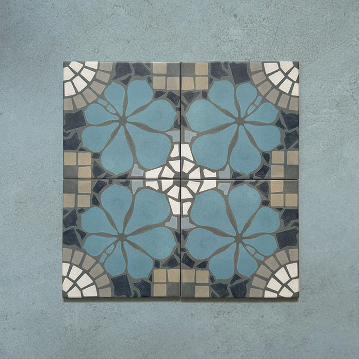 Four Bloom Azul Blue 20x20cm Moroccan-style ceramic tiles displayed together, featuring a symmetrical floral pattern in blue, grey, beige, and white tones on a textured blue background.