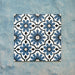 Flatlay featuring four Clarence House Azul Blue 20x20cm Victorian Moroccan-style porcelain tiles, forming a repeating blue and white geometric floral pattern on a textured blue background.