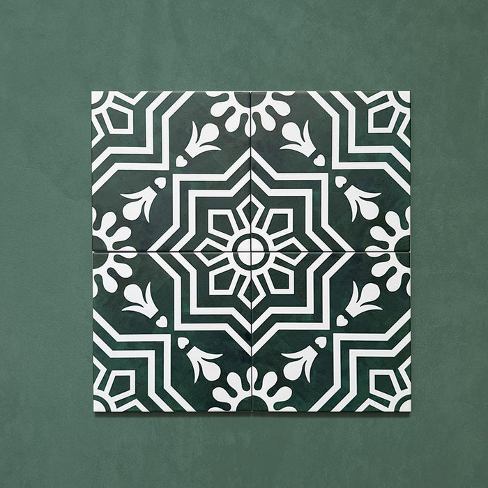 Four Brompton Victorian Green 20x20cm geometric patterned ceramic tiles displayed together, featuring a symmetrical white floral and star motif on a deep green background, shown against a matching green surface.