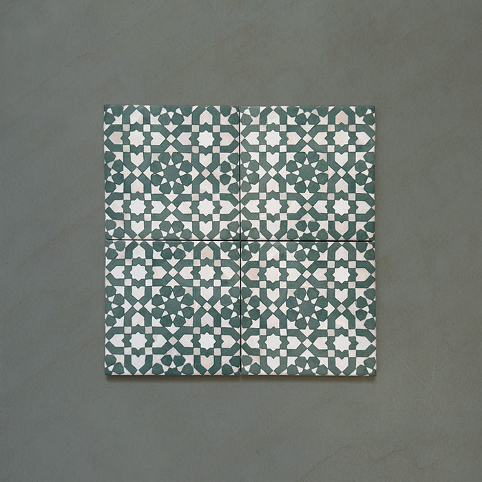 Bedouin Tetuan Green Moroccan-style 15x15cm set of four tiles showing a repeating geometric star and cross motif in deep green, soft beige, and white tones with a handcrafted matte finish and subtle texture.