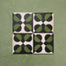 Group image showing four Geometry Illusion Verde Noir 20x20cm geometric patterned tiles arranged to create a circular repeat, featuring green and black semicircles with cream diamond intersections, photographed against a mottled green background.