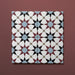 Close-up of four Agraba Mini Atlas 15x15cm Moroccan-style ceramic tiles showing a geometric star pattern in blue, terracotta, black, and white tones on a warm burgundy background.