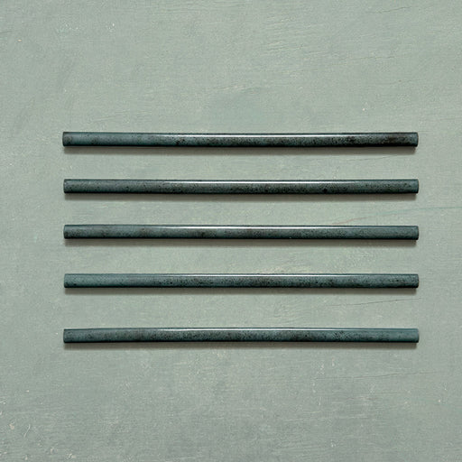 Five Izmir Green Gloss Pencil Bullnose Border Tiles 1.2x30cm arranged on a soft green background, showcasing their curved edges and rich, handcrafted effect glossy finish.