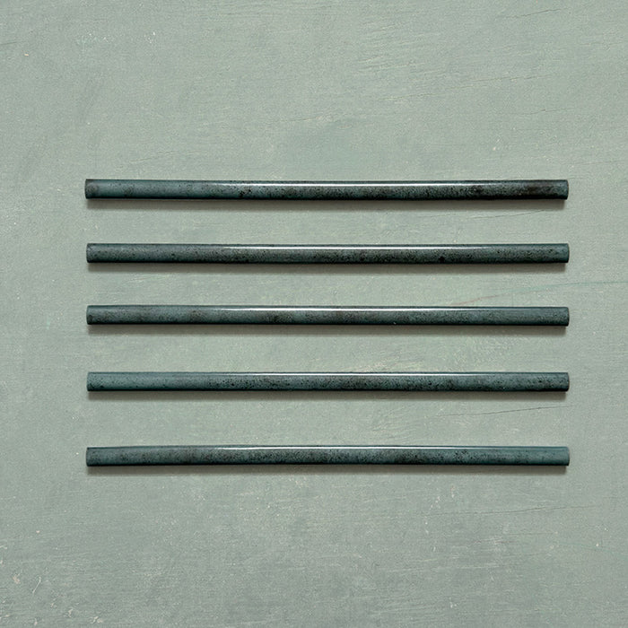 Five Izmir Green Gloss Pencil Bullnose Border Tiles 1.2x30cm arranged on a soft green background, showcasing their curved edges and rich, handcrafted effect glossy finish.