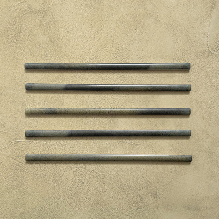 Five Izmir Daisy Green Gloss Pencil Bullnose Border Tiles 1.2x30cm displayed on a textured beige background, showing subtle shade variation and a smooth rounded glossy finish.