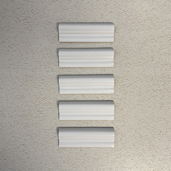 Flat lay of Finchley White ceramic dado trim tiles in a 5 × 15cm format, featuring a crackle glaze finish that adds subtle texture and a decorative, classic detail to wall tile designs.