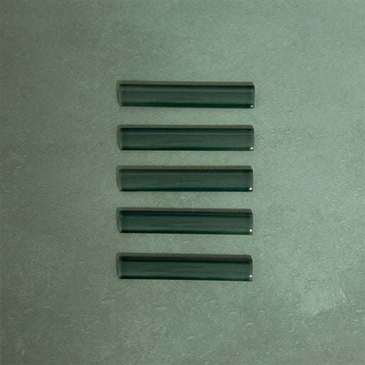 Flat lay of Finchley Golders Green ceramic pencil trim tiles in a 2.5 × 15cm format, featuring a crackle glaze finish that adds subtle texture and a refined decorative edge to wall tile designs.