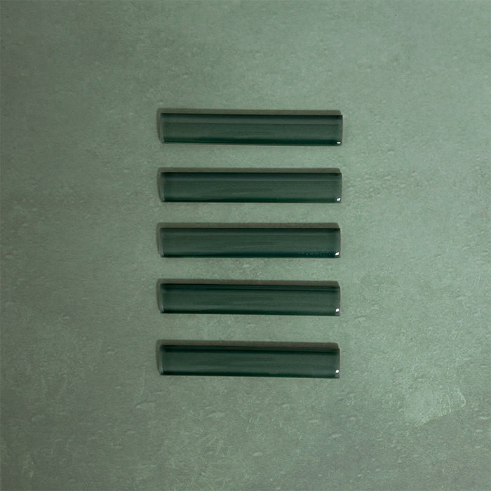 Flat lay of Finchley Golders Green ceramic pencil trim tiles in a 2.5 × 15cm format, featuring a crackle glaze finish that adds subtle texture and a refined decorative edge to wall tile designs.