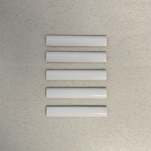 Flat lay of Finchley White ceramic pencil trim tiles in a 2.5 × 15cm format, featuring a crackle glaze finish that adds subtle texture and a refined decorative edge to wall tile installations.