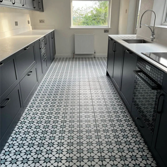 Kitchen featuring Agraba Azul Blue 20x20cm Moroccan-style ceramic floor tiles with a navy geometric star pattern, styled with dark grey cabinetry, white countertops, and chrome fixtures for a modern contrast.