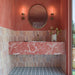 Agraba Azul Blue 20cm x 20cm Moroccan style tiles used across a bathroom floor, featuring a bold blue and white geometric pattern, paired with soft pink wall tiles, coral-toned walls and a statement marble vanity.