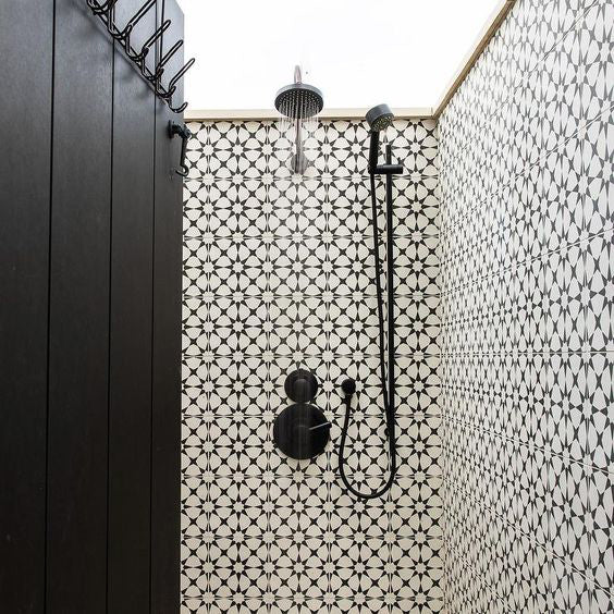 Walk-in shower featuring Agraba Black and White 20x20cm Moroccan-style ceramic wall tiles, with black rainfall shower system and matching painted wooden door.