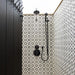 Walk-in shower featuring Agraba Black and White 20x20cm Moroccan-style ceramic wall tiles, with black rainfall shower system and matching painted wooden door.