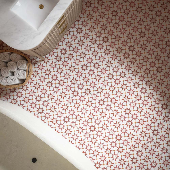 Close-up of Agraba Cotto 20cm x 20cm Moroccan-style floor tiles, featuring a geometric terracotta and white pattern, styled with a bathroom vanity and woven towel basket.