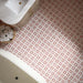 Close-up of Agraba Cotto 20cm x 20cm Moroccan-style floor tiles, featuring a geometric terracotta and white pattern, styled with a bathroom vanity and woven towel basket.