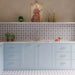 Agraba Mini Atlas 15cm x 15cm Moroccan style tiles, featuring a repeating geometric pattern in soft blue, burgundy and white across the kitchen splashback and floor, paired with pale blue cabinetry and brass details.