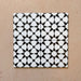 Close-up of four Agraba Black and White Mini 15x15cm Moroccan-style ceramic tiles arranged together, showing the repeating geometric star pattern and clean matt finish on a neutral surface.