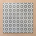Close-up of multiple Agraba Black and White Mini 15x15cm Moroccan-style ceramic tiles arranged in a grid, showcasing their bold geometric star pattern and smooth matt surface on a neutral background.