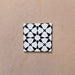 Close-up of Agraba Black and White Mini 15x15cm Moroccan-style ceramic tile featuring a bold geometric star pattern in black and white on a neutral background.
