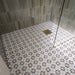 Walk-in shower featuring Agraba Natural Moroccan style patterned floor tiles, paired with sage green vertically laid wall tiles, a frameless glass shower screen and brushed brass shower fittings for a contemporary, Mediterranean-inspired bathroom.