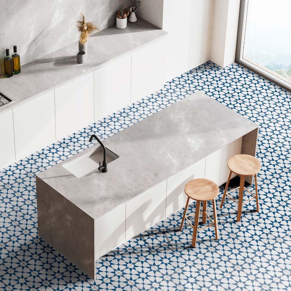 Modern kitchen featuring Agraba Navy 20x20cm Moroccan-style ceramic floor tiles in blue and white, paired with sleek white cabinets, marble-effect countertops, and wooden bar stools for a clean coastal look.