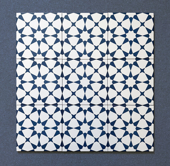 Close-up of multiple Agraba Navy 20x20cm Moroccan-style ceramic tiles arranged in a grid, showcasing a repeating geometric star pattern in navy blue and white on a dark background.