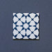 Close-up of Agraba Navy 20x20cm Moroccan-style ceramic tile featuring a bold geometric star pattern in deep navy blue and white on a textured dark background.