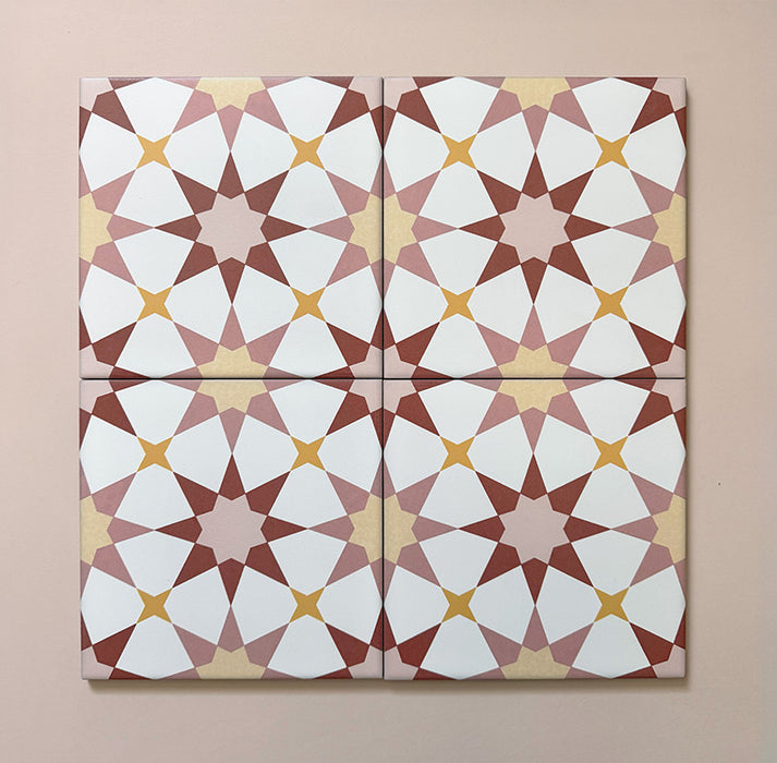 Close-up of four Agraba Springs 20x20cm Moroccan-style ceramic tiles showing a geometric star pattern in terracotta, blush pink, mustard, and white tones on a soft pastel background.
