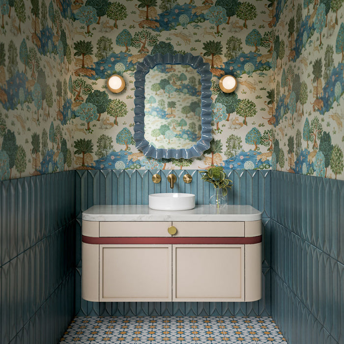 Agraba Sunshine 20cm x 20cm Moroccan style tiles, featuring an intricate geometric pattern in blue, white and warm ochre across the bathroom floor, paired with sculpted blue wall tiles and botanical wallpaper.