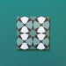 Single Agraba Verde 20x20cm Moroccan-style ceramic tile with a geometric star pattern in deep green, mint, and white tones, displayed on a teal background to highlight its intricate artisan design.