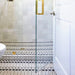 Alhambra Felisa 20x20cm Moroccan tiles used in a walk-in shower, featuring a striking black and white geometric pattern paired with neutral wall tiles and gold accents for a clean, contemporary Moroccan style.