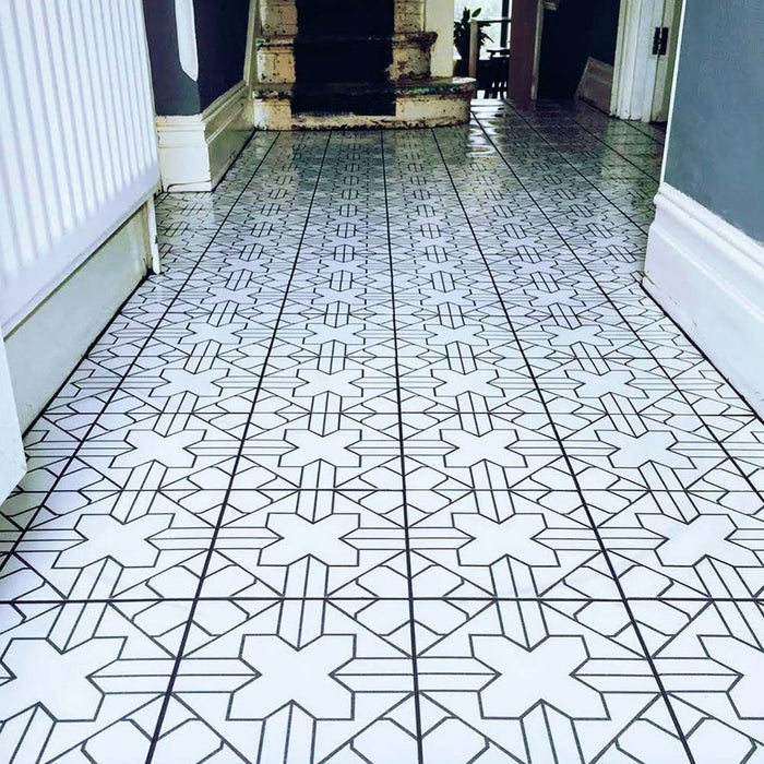Alhambra Palacio 20x20cm Moroccan tiles used in a hallway, featuring a detailed black geometric cross pattern on a white background for a refined, statement floor design.