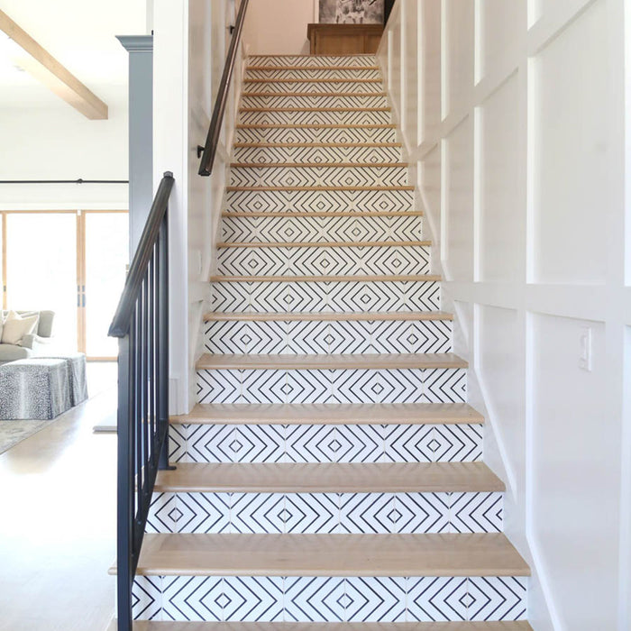 Alhambra Zig Zag Blanco 20x20cm Moroccan tiles used on a staircase with wooden steps and white panelled walls, featuring a bold black and white chevron pattern that adds a modern geometric accent to the hallway.