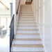 Alhambra Zig Zag Blanco 20x20cm Moroccan tiles used on a staircase with wooden steps and white panelled walls, featuring a bold black and white chevron pattern that adds a modern geometric accent to the hallway.